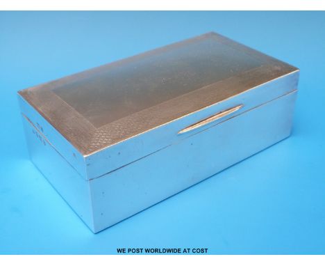 A hallmarked silver cigarette box with engine turned border, width 16.5cm (550g)