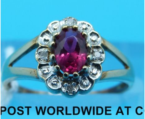 A 9ct gold ring set with an oval ruby surrounded by diamonds (Size N)