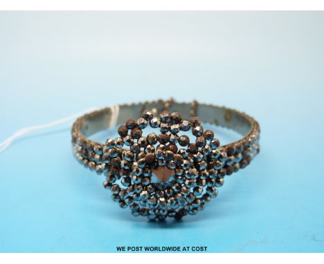 A Victorian cut steel and white metal bangle formed of three rows of single faceted stones mounted with a tiered circular pan