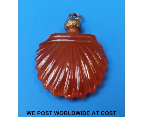 A carved carnelian agate scent bottle of scallop shell form with engine turned stopper and yellow metal suspension loop