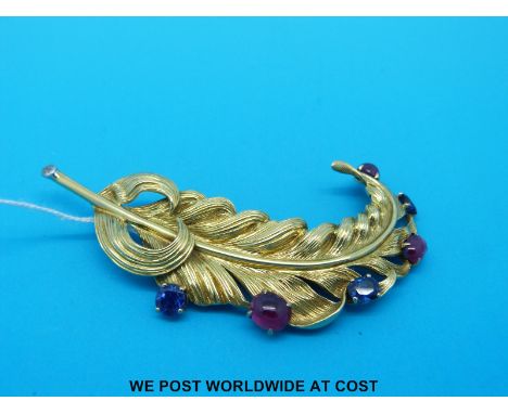 A large yellow metal brooch in the form of a feather plume with textured design set with three ruby cabochons and three oval 