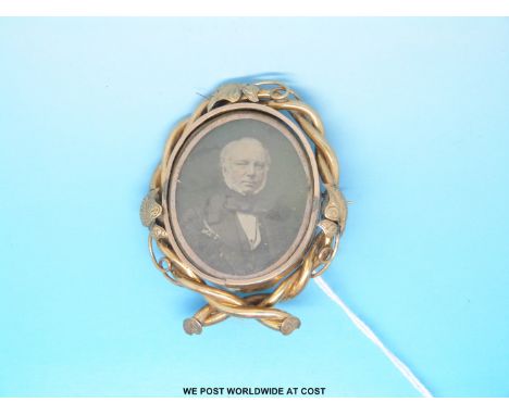 A Victorian swivel brooch set with a daguerreotype portrait of a gentleman in  a foliate scrolling border