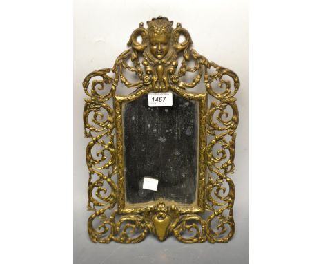 An ornate 19th century brass mirror, cast with the head of a lady