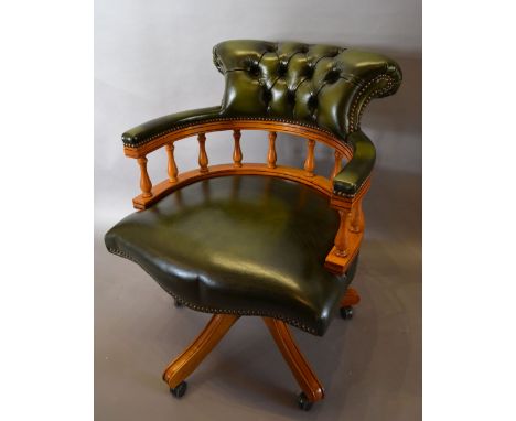A Reproduction Green Leather Revolving Office Armchair with a button upholstered back raised upon outswept legs