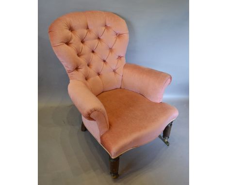An Upholstered Drawing Room Chair with a button upholstered back raised upon turned legs with brass caps and castors
