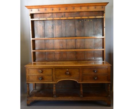 A George III Oak Dresser, the boarded shelf back above five drawers with knob handles above an under tier with turned taperin