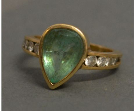 An Unmarked Gold Dress Ring set with a teardrop emerald flanked by diamonds, 6.3 gms