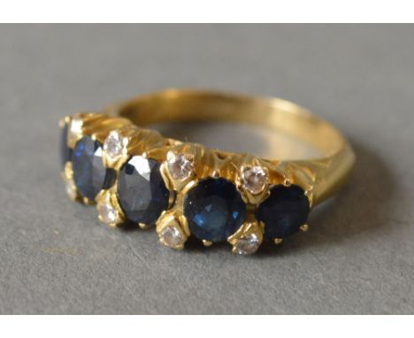 An 18ct Yellow Gold Sapphire and Diamond Band Ring set with five sapphires flanked by eight diamonds within a pierced setting