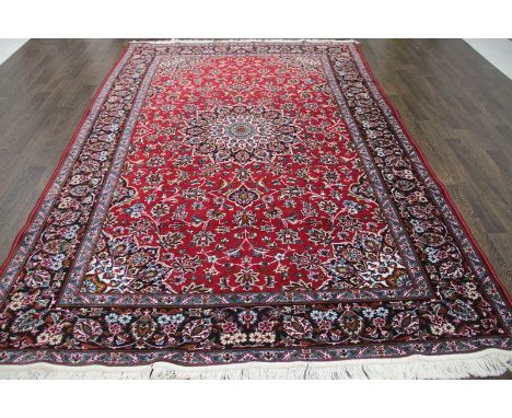 A North West Persian Woollen Carpet with a central medallion within an all over design upon a red, blue and cream ground with