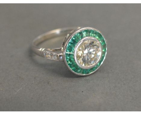 A 14ct White Gold Emerald and Diamond Ring, the central diamond surrounded by emeralds and with diamond shoulders, solitaire 