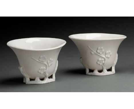 Paar Dehua-Weinbecher mit Prunus- und Magnolien-Blüten in Relief auf Astwerk ruhend, miulchig weiss glasiertChina, Chongzhen 