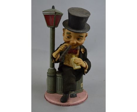 A JAPANESE TINPLATE AND PLASTIC BATTERY OPERATED AUTOMATON FIGURE AND LAMP, gentleman in top hat and tails sitting on a dustb