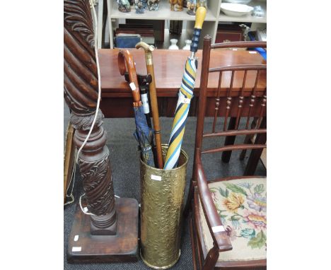 A brass stick stand containing modern umbrellas and sticks
