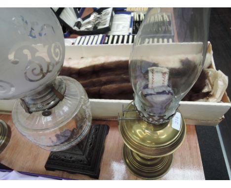 A brass oil lamp and chimney, and a cast oil lamp with etched glass reservoir and shade