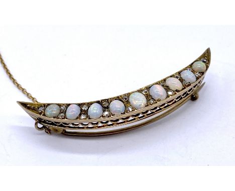 An antique opal and diamond crescent moon brooch in yellow metal, set with graduating cabochon opals and accented by rose cut