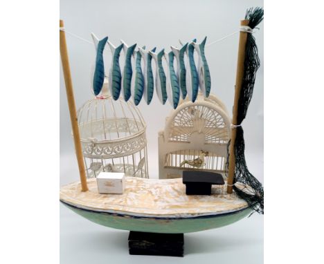 A wooden bird cage along with a similar metal cage and a model of a fishing boat.
