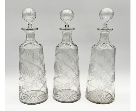 A set of three 19th century etched "Gin", "Whisky" and "Brandy" decanters with cut glass bases and floral motifs 