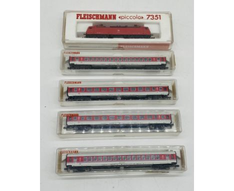 A cased Fleischmann Piccolo N gauge diesel-electric locomotive in red livery (7351), along with four cased Fleischmann carria