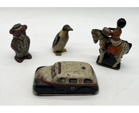 A collection of vintage tin plate clockwork toys including a penguin, Joytown Ambulance, Teddy Bear and mounted drummer (arm 