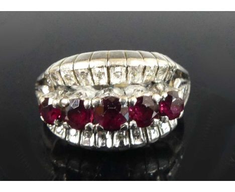 A white metal ruby and diamond three-row half-hoop ring, having five graduated round cut rubies within a border of 22 single 