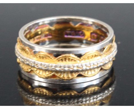 A 22ct and platinum openwork band ring featuring a central textured yellow circular pattern with an engraved white band runni