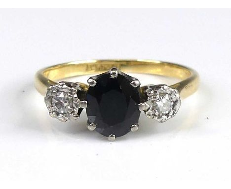 A yellow and white metal, sapphire and diamond three-stone ring, comprising an oval sapphire in a claw setting flanked to eit