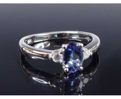 A contemporary 14ct white gold, tanzanite and diamond set dress ring, the four-claw set oval cut tanzanite measuring 6.6 x 4.