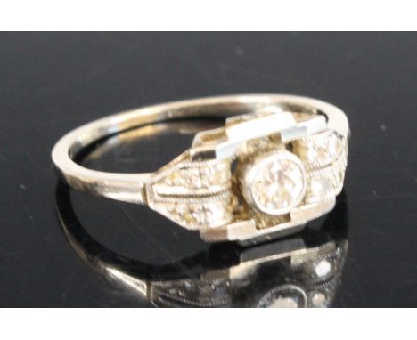 An Art Deco style white metal diamond panel ring featuring a centre round brilliant cut diamond in a bezel setting with 2 row