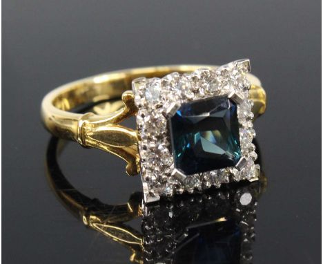 An 18ct yellow and white gold, synthetic sapphire and diamond square cluster ring, featuring a centre square cut synthetic sa