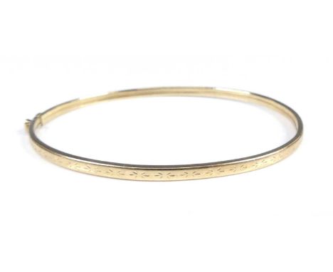 A modern 9ct gold hinged bangle, having carved decoration, band w.2.7mm, dia.6.4cm, 3.6g