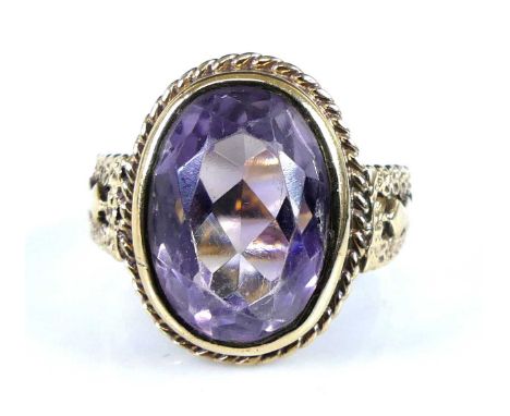 A 9ct yellow gold amethyst set dress ring, the oval amethyst in a bezel setting with ropetwist surround and pierced shoulders
