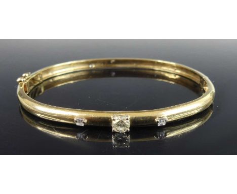A modern 9ct gold diamond set hinged bangle, the hollowed oval band centre four-claw set with a round brilliant cut diamond w