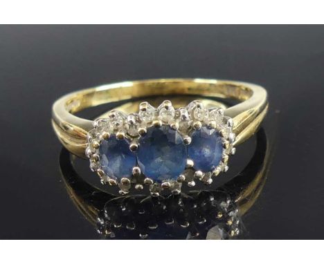 A 9ct yellow and white gold, sapphire and diamond triple cluster ring, featuring three graduated oval sapphires within a bord