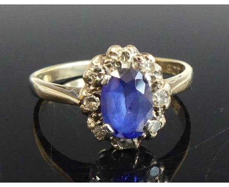 A yellow and white metal, sapphire and diamond oval cluster ring, featuring a centre oval sapphire within a border of eight s