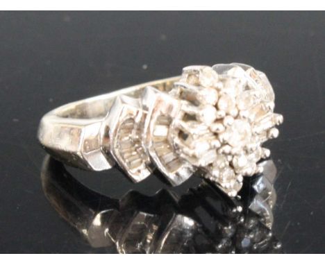 A white metal diamond navette style cluster ring comprising 7 round brilliant cut diamonds and 6 baguette cut diamonds with s