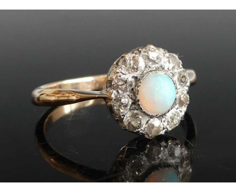 A yellow and white metal, opal and diamond circular cluster ring, featuring a centre opal cabochon within a border of ten Old
