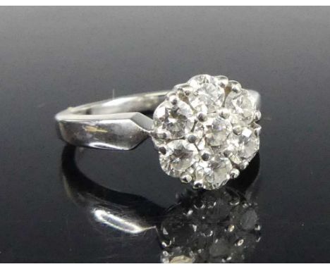 An 18ct white metal diamond flower head cluster ring, arranged as seven round brilliant cuts, the centre stone weighing appro