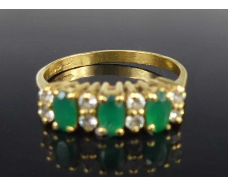 An 18ct gold, emerald and diamond half-hoop ring, arranged as three four-claw set oval cut emeralds, each measuring approx 5 