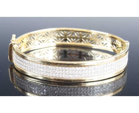 A modern 14ct gold cz set hinged bangle, one side set with three rows of small round cut cubic zirconia, the other side with 