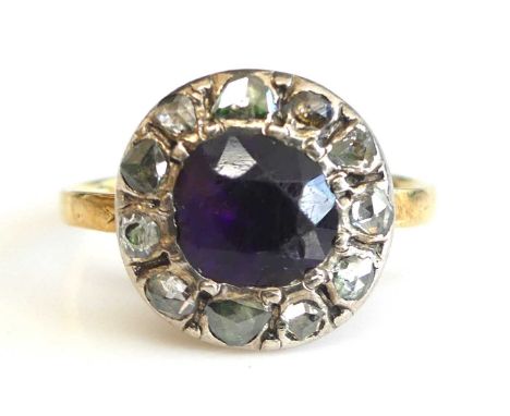 A late Georgian yellow and metal circular cluster ring with a centre 6.9mm purple paste stone within a border of rose cut dia