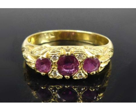 An Edwardian style ruby and diamond ring, the three graduated round cut rubies in a carved setting, the centre ruby weighing 