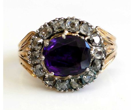 A late Victorian yellow and white metal amethyst and diamond oval cluster ring featuring an oval cut amethyst in a horizontal