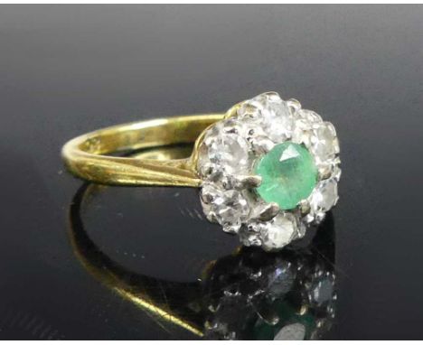 An 18ct gold and platinum, emerald and diamond flower head cluster ring, the centre round cut emerald weighing approx 0.25 ca
