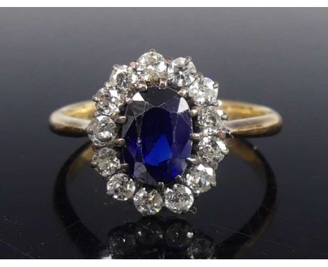 A yellow and white metal, synthetic sapphire and diamond oval cluster ring, the synthetic sapphire measuring approx 8.2 x 5.8
