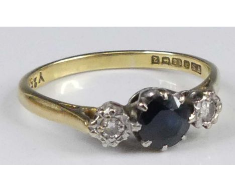 An 18ct gold sapphire and diamond three stone ring, the centre round cut sapphire measuring approx 5.4x3.1mm, flanked to eith