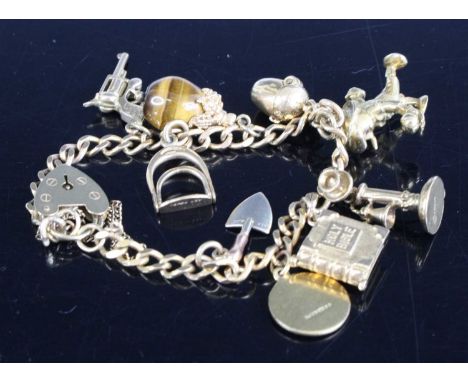 A 9ct yellow gold filed curblink bracelet, with padlock, safety chain and the following charms; pistol, stirrup, tiger's eye 