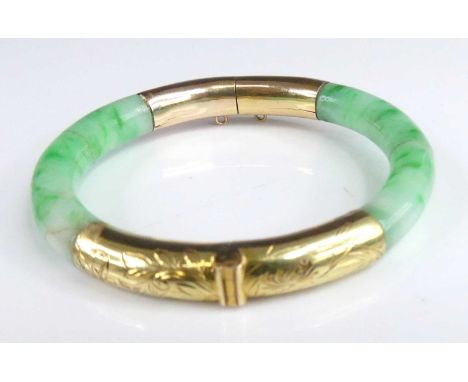 An 18ct gold mounted celadon and green jade hinged bangle (repaired twice to jade), the gold hinged mounts with leaf and flow