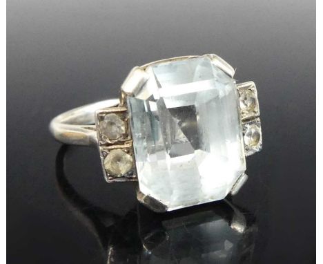 A white metal aquamarine dress ring, the octagonal cut aquamarine in a four-claw setting, flanked by two 2.5mm round cubic zi