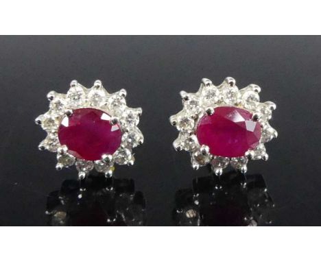 A pair of 18ct yellow and white gold, ruby and diamond oval cluster stud earrings, each with an oval ruby within a border of 