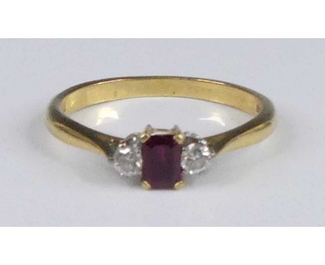 An 18ct gold ruby &amp; diamond three stone dress ring comprising a step cut ruby, flanked by two round brilliant cut diamond